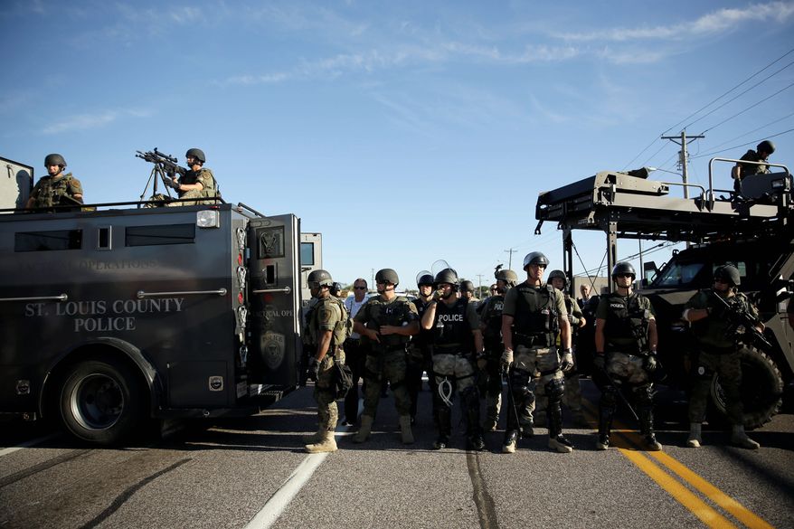 Police in riot gear watch protesters in Ferguson, Missouri. The transfer program is under intense scrutiny in the aftermath of this month&#39;s standoffs between police and protesters. (Associated Press photographs)