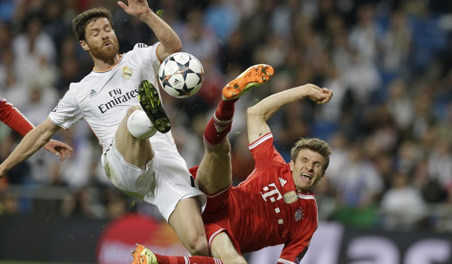 Real&#x27;s Xabi Alonso, left, and Bayern&#x27;s Thomas Mueller challenge for the ball during a  Champions League semifinal first leg soccer match between Real Madrid and Bayern Munich at the Santiago Bernabeu stadium in Madrid, Spain, Wednesday, April 23, 2014 .(AP Photo/Paul White)