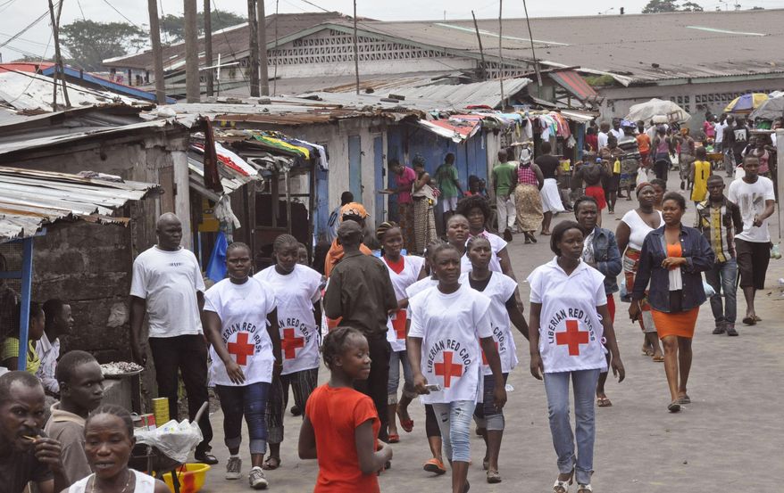 In this photo taken on Wednesday, Aug. 27, 2014, Red Cross workers walk through a section of West Point, an area that has been hit hard by the Ebola virus, with residents not allowed to leave as government forces clamp down on movement to prevent the spread of Ebola, in Monrovia, Liberia. The Ebola outbreak in West Africa eventually could exceed 20,000 cases, more than six times as many as are now known, the World Health Organization said Thursday. A new plan released by the U.N. health agency to stop Ebola also assumes that the actual number of cases in many hard-hit areas may be two to four times higher than currently reported. (AP Photo/Abbas Dulleh)