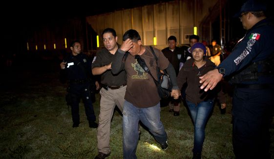 Immigration officials detain Central American migrants during a raid by federal police on a northbound freight train, in San Ramon, Mexico, just after midnight on Friday, Aug. 29, 2014. Migrants captured in raids are deported to their home countries. The largest crackdown by Mexican authorities on illegal migration in decades has decreased the flow of Central American migrants trying to reach the United States, and has dramatically cut the number of child migrants and families, according to officials and eyewitness accounts along the perilous route.(AP Photo/Rebecca Blackwell)