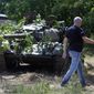 A local resident passes by camouflaged pro-Russian tank in the town of Novoazovsk, in eastern Ukraine, Friday, Aug. 29, 2014. In Novoazovsk, pro Russian rebel fighters looked to be in firm control, well-equipped and relaxed. At least half a dozen tanks were seen on roads around the town, although the total number at the rebels&amp;#8217; disposal is believed to be much greater. Novoazovsk fell swiftly to the rebels Wednesday after being pounded by shelling.(AP Photo/Sergei Grits)