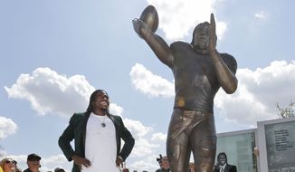 Washington Redskins quarterback Robert Griffin III looks at a bronze statute of himself after it was unveiled outside the new McLane Stadium before an NCAA college football game between SMU and Baylor Sunday, Aug. 31, 2014, in Waco, Texas. Griffin won the Heisman Trophy when he played at Baylor. (AP Photo/LM Otero)  