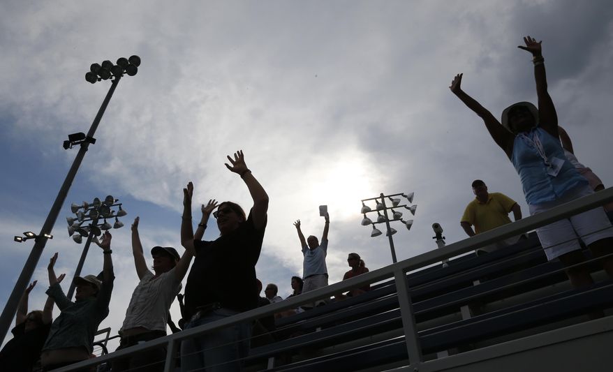 Fans cheer play as storm clouds begin to roll over the Billie Jean King National Tennis Center during the 2014 U.S. Open tennis tournament, Sunday, Aug. 31, 2014, in New York. (AP Photo/Elise Amendola)