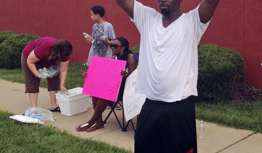 In this Aug. 23, 2014 photo, Lamont Jones holds up a sign reading "Darren Wilson is a Murderer," in St. Louis. Jones was reacting to a rally supporting Wilson, the white officer who shot unarmed, black 18-year-old Michael Brown in Ferguson, Mo. Like many Americans, Jones has formed concrete opinions about the case. (AP Photo/Jesse Washington)