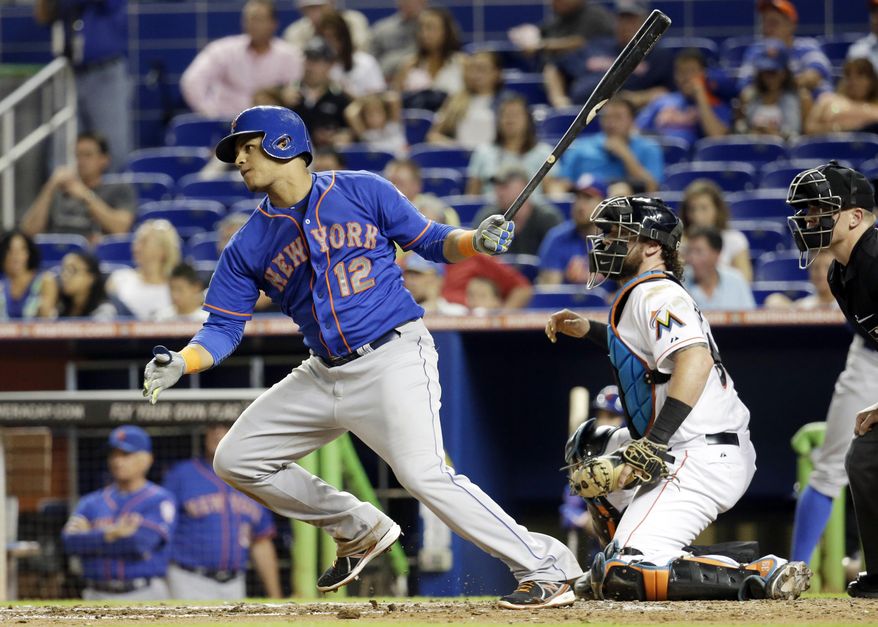New York Mets' Juan Lagares (12) watches after hitting a RBI singe to score Wilmer Flores in the fourth inning during a baseball game, Tuesday, Sept. 2, 2014, in Miami. At right is Miami Marlins catcher Jarrod Saltalamacchia. (AP Photo/Lynne Sladky)