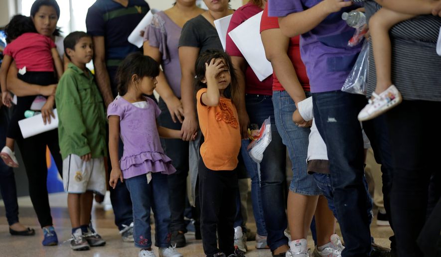 In this June 20, 2014, file photo, immigrants who entered the U.S. illegally stand in line for tickets at the bus station after they were released from a U.S. Customs and Border Protection processing facility in McAllen, Texas. The immigrants entered the country through an area referred to as zone nine. (AP Photo/Eric Gay) ** FILE **
