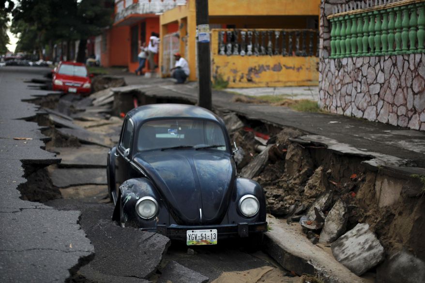 Cars sit on a street that collapsed after heavy rain in the Gulf port city of Veracruz, Mexico, Tuesday, Sept. 2, 2014. The Gulf states of Mexico are bracing for more bad weather as Tropical Storm Dolly crosses the coast and continues moving inland over northeastern Mexico on Wednesday. (AP Photo/Felix Marquez)