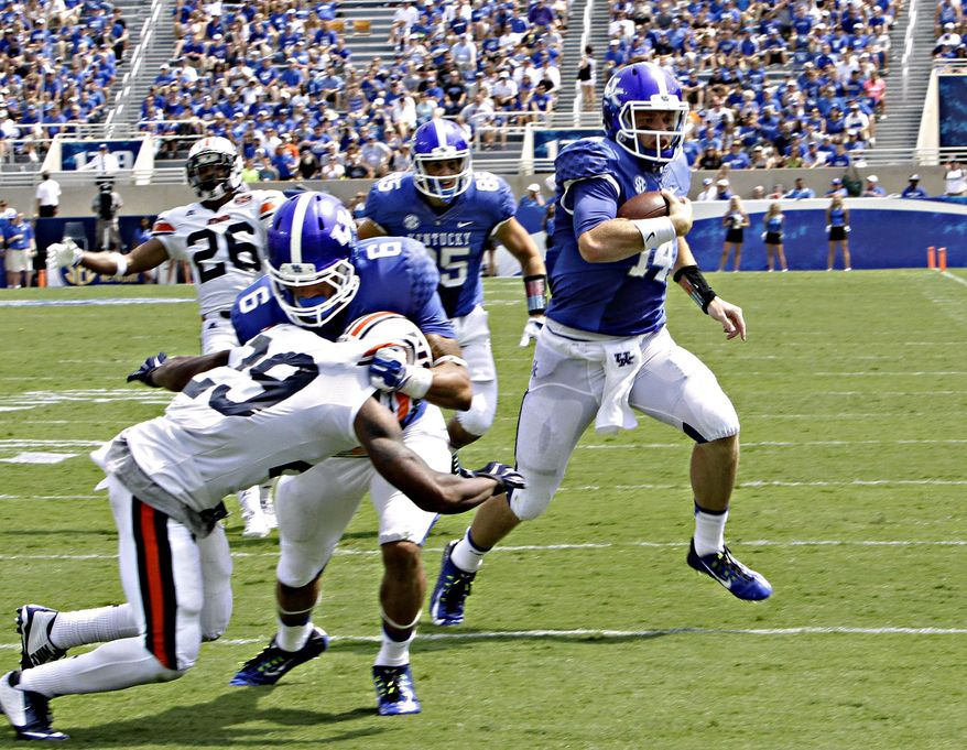 Kentucky quarterback Patrick Towles (14) sprints to the end zone to score a touchdown as teammate Blake Bone (56) blocks Tennessee-Martin's Aaron Simms (29) in the second half of an NCAA college football game in Lexington, Ky., Saturday, Aug. 30, 2014. (AP Photo/Garry Jones)