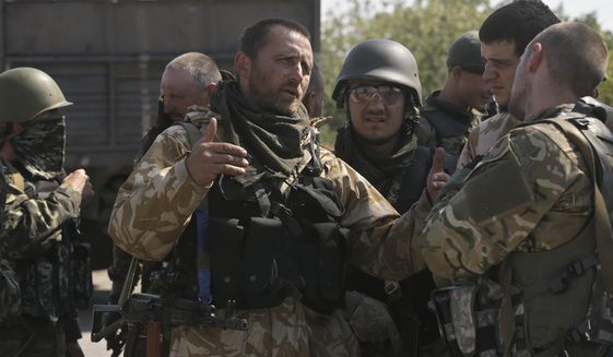 Soldiers of special battalion &quot;Azov&quot;; talk at a checkpoint in the port city of Mariupol, southeastern Ukraine, Friday, Sept. 5, 2014. Shelling resounded on the outskirts of the city Friday as Russian-backed rebels pressed their offensive in the strategically key southeast just hours ahead of talks that are widely hoped to bring a cease-fire. Associated Press reporters heard heavy shelling on Friday morning north and east of Mariupol. (AP Photo/Sergei Grits)