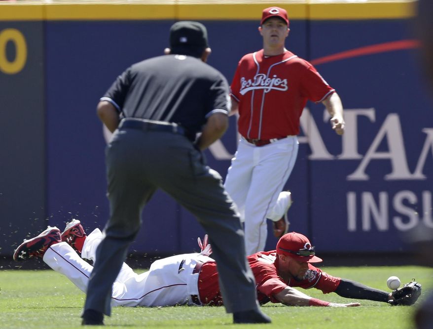 Cincinnati Reds center fielder Billy Hamilton dives between umpire Alfonso Marquez and right fielder Jay Bruce just missing a base hit by New York Mets' Kirk Nieuwenhuis in the first inning of a baseball game, Sunday, Sept. 7, 2014, in Cincinnati. (AP Photo/Al Behrman)