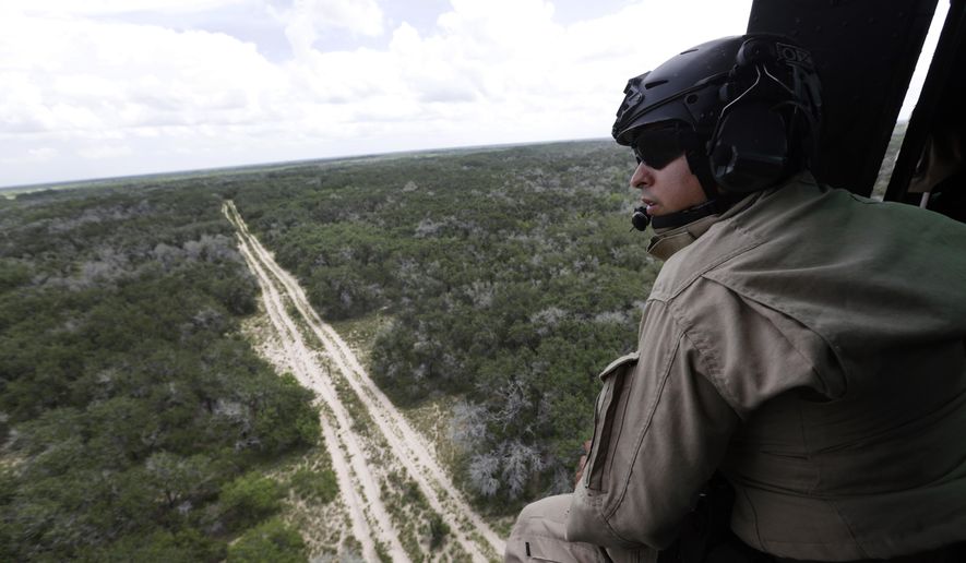 A U.S. Customs and Border Protection Air and Marine agent peers out of the open door of a helicopter during a patrol flight near the Texas-Mexico border. (AP Photo)
