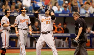 Umpire Greg Gibson, right, Baltimore Orioles left fielder David Lough,left, and  Chris Davis (19) watch as designated hitter Nelson Cruz (23) celebrates his two run home run during the sixth inning of a baseball game against the Tampa Bay Rays on Sunday, Sept. 7, 2014 in St. Petersburg, Fla.. (AP Photo/Reinhold Matay)