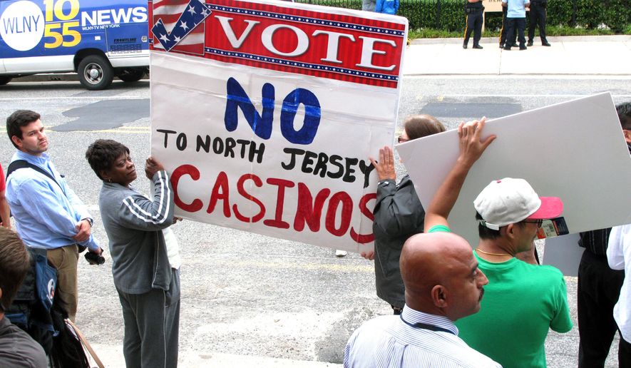 Protestors hold signs across the street from a meeting New Jersey Gov. Chris Christie convened on Monday Sept. 8, 2014 on the future of Atlantic City. The meeting came hours after Christie's administration said it will allow the state's casinos and horse tracks to offer sports betting, a move certain to be challenged in court by the professional and collegiate sports leagues. (AP Photo/Wayne Parry)