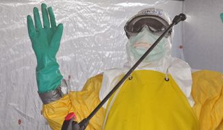 A health worker is sprayed with disinfectant after he worked with patients that contracted the Ebola virus, at a clinic  in Monrovia, Liberia, Monday, Sept. 8, 2014.  Border closures, flight bans and mass quarantines are creating a sense of siege in the West African countries affected by Ebola, officials at an emergency African Union meeting said Monday, as Senegal agreed to allow humanitarian aid pass through its closed borders. (AP Photo/Abbas Dulleh)