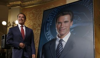 Former Gov. Arnold Schwarzenegger poses with his official portrait after it was unveiled at the Capitol in Sacramento, Calif., Monday, Sept. 8, 2014. The photograph-like giant image of the former governor was done by Austrian artist Gottfried Helnwein and will hang on the third floor of the Capitol. (AP Photo/Rich Pedroncelli)