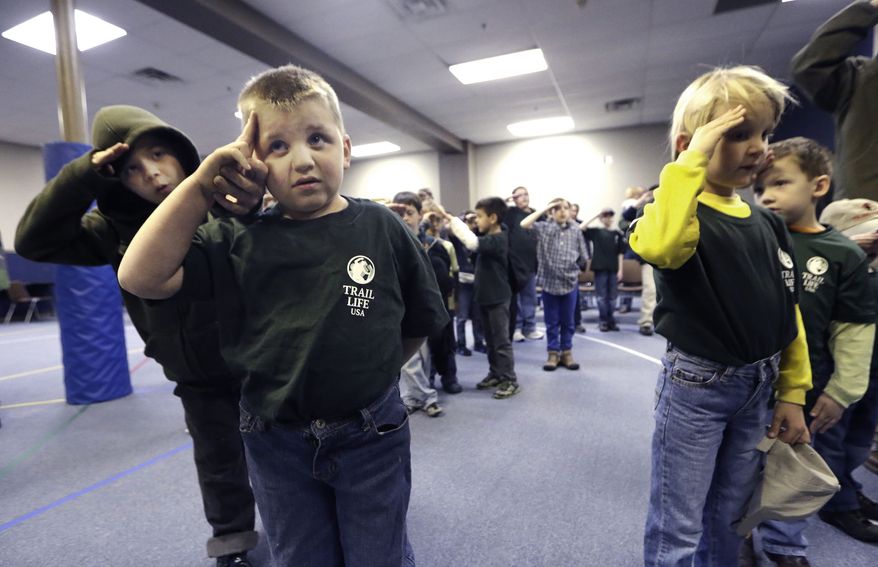 In this Tuesday, Feb. 4, 2014 photo, Trail Life member Adrian McCade, 7, second from left, gets direction on hand placement for the salute from his older brother Jack McCade, 8, during a group meeting in North Richland Hills, Texas. John Stemberger, an Orlando, Fla. lawyer who led the opposition to the Boy Scouts of America&#39;s May 2013 vote to accept openly gay youth, went on to found Trail Life. (AP Photo/LM Otero)