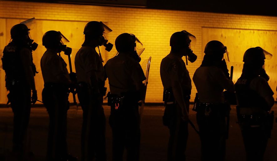 FILE - In this Aug. 17, 2014 file photo, police wait to advance after tear gas was used to disperse a crowd during a protest for Michael Brown, who was killed by a police officer Aug. 9 in Ferguson, Mo. The Ferguson City Council, set to meet Tuesday, Sept. 9, 2014, for the first time since the fatal shooting of Brown, said it plans to establish a review board to help guide the police department and make other changes aimed at improving community relations. (AP Photo/Charlie Riedel, File)
