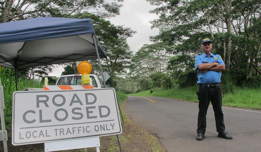 In this Monday, Sept. 8, 2014 photo, security guard George Cortez stands at a roadblock to prevent non-residents from entering the lava-threatened community of Kaohe Homesteads in Pahoa, Hawaii. Those who live on the slopes of Kilauea volcano know lava could start creeping their way at any time but the area is still a powerful draw for many people who value its community and affordability. (AP Photo/Audrey McAvoy)