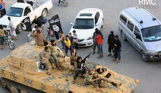 ** FILE ** In this undated file image posted by the Raqqa Media Center, a Syrian opposition group, on Monday, June 30, 2014, which has been verified and is consistent with other AP reporting, fighters from Islamic State group sit on their tank during a parade in Raqqa, Syria. (AP Photo/Raqqa Media Center, File)