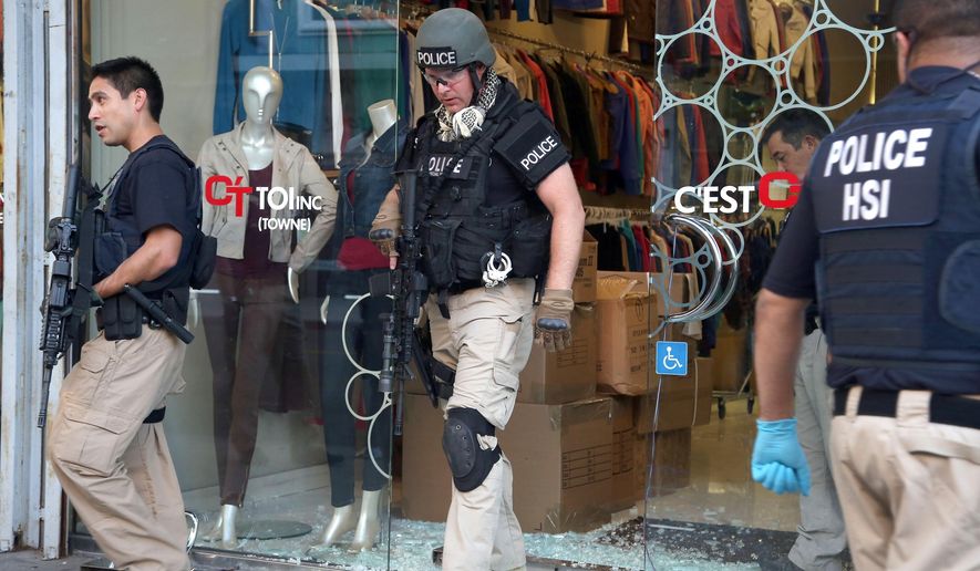 Law enforcement agents leave a clothing store after a raid in the Los Angeles Fashion District Wednesday, Sept. 10, 2014. U.S. agents raided dozens of businesses in the fashion district of Los Angeles early Wednesday as part of an investigation into suspected money laundering done for Mexican drug cartels. (AP Photo/ Nick Ut )