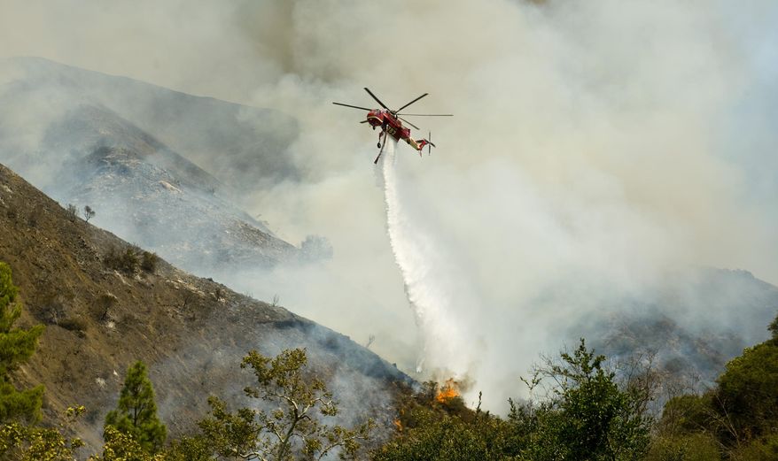 An Orange County Fire Authority helicopter drops a load of water on a brush fire in Silverado Canyon in Orange County, Calif. on Friday, Sept. 12, 2014. (AP Photo/Orange County Register, Sam Gangwer)