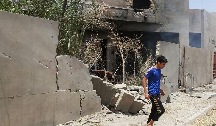 FILE - in this Saturday, July 19, 2014 file photo Abdullah Ahmed walks outside his home that was damaged in a bombing, in Fallujah, 40 miles (65 kilometers) west of Baghdad, Iraq. Iraq's prime minister Haider al-Abadi said Saturday he has ordered the army to stop shelling populated areas held by militants in order to spare the lives of "innocent victims" as the armed forces struggle to retake cities and towns seized by fighters of the Islamic State extremist group this summer. (AP Photo, File)