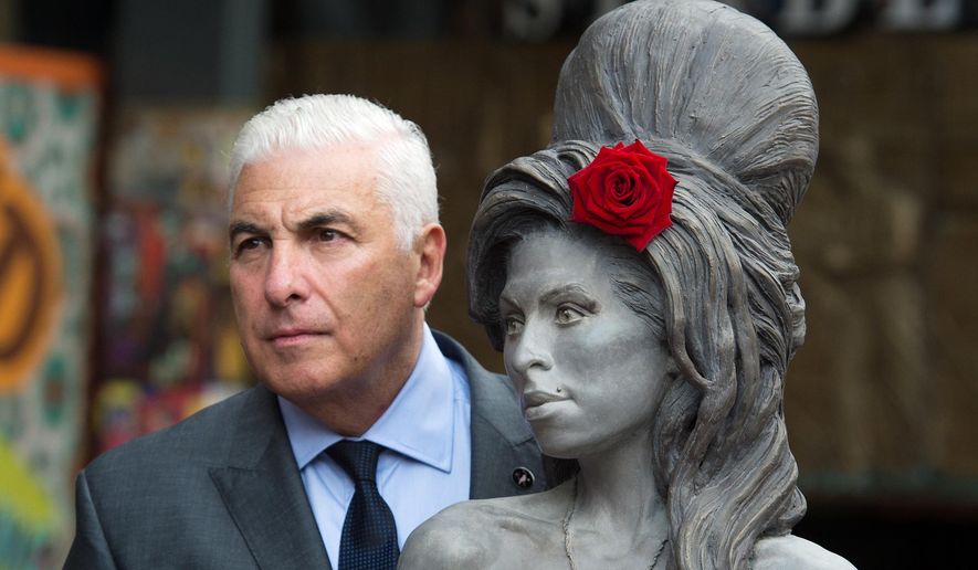 Mitch Winehouse poses for a picture with a statue of his late daughter, Amy Winehouse after it was unveiled in Camden's Stables Market, in London, England, Sunday, Sept. 14, 2014. Three years after her death the unveiling coincides with what would have been her 31st birthday. (AP Photo/Tim Ireland)