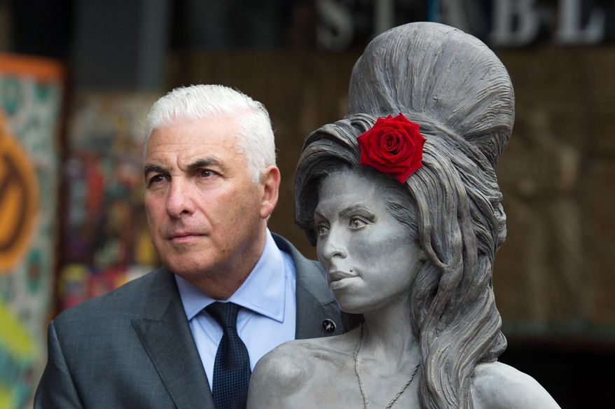 Mitch Winehouse poses for a picture with a statue of his late daughter, Amy Winehouse after it was unveiled in Camden's Stables Market, in London, England, Sunday, Sept. 14, 2014. Three years after her death the unveiling coincides with what would have been her 31st birthday. (AP Photo/Tim Ireland)