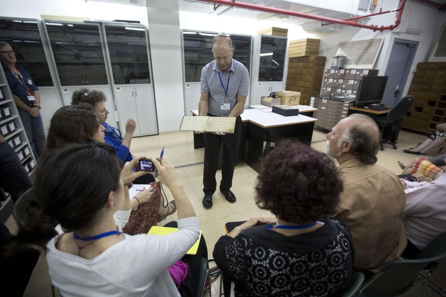 In this Monday, Sept. 8, 2014 photo, Yad Vashem's archive director Haim Gertner show's a document to visiting international experts and others who are participating in a workshop devoted to the physical and digital preservation of documents, in Jerusalem. With Holocaust survivors dying in growing numbers and their live testimonies soon to be a thing of the past, Holocaust commemoration efforts are increasingly focusing around preserving the belongings that contain their stories. (AP Photo/Sebastian Scheiner)