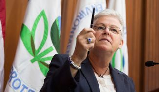 Environmental Protection Agency (EPA) Administrator Gina McCarthy holds up a pen before signing new emission guidelines during an announcement of a plan to cut carbon dioxide emissions from power plants by 30 percent by 2030, Monday, June 2, 2014, at EPA headquarters in Washington.  In a sweeping initiative to curb pollutants blamed for global warming, the Obama administration unveiled a plan Monday that cuts carbon dioxide emissions from power plants by nearly a third over the next 15 years, but pushes the deadline for some states to comply until long after President Barack Obama leaves office. (AP Photo/ Evan Vucci)