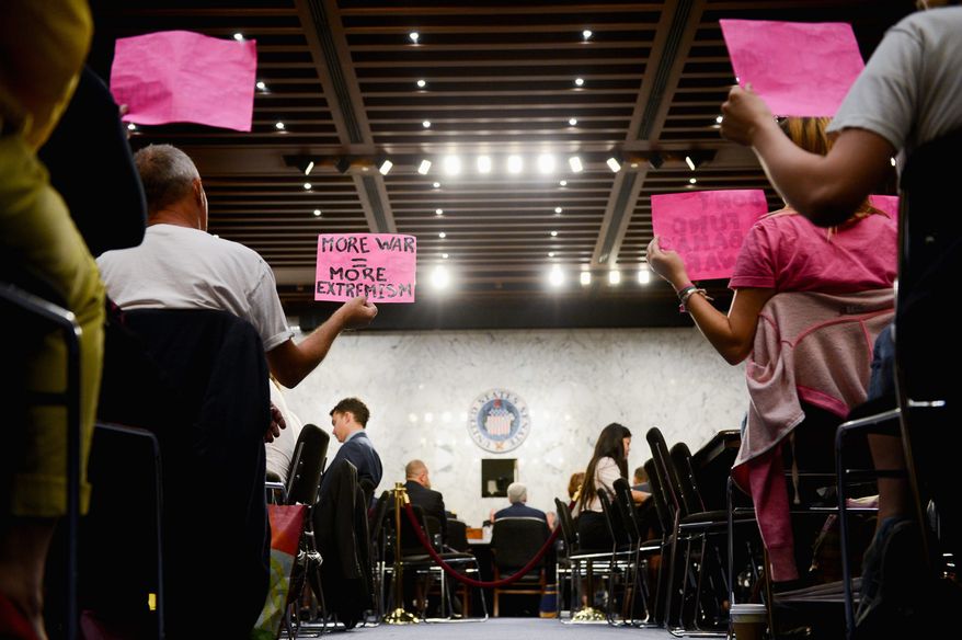 Members of the protest group Code Pink hold anti-war signs as Secretary of Defense Chuck Hagel and the Chairman of the Joint Chiefs of Staff Martin Dempsey testify on Islamic State militants in front of the Senate Armed Services Committee. Gen. Dempsey opened the door to the possibility that U.S. combat troops would be needed in Iraq. (Andrew Harnik/The Washington Times)
