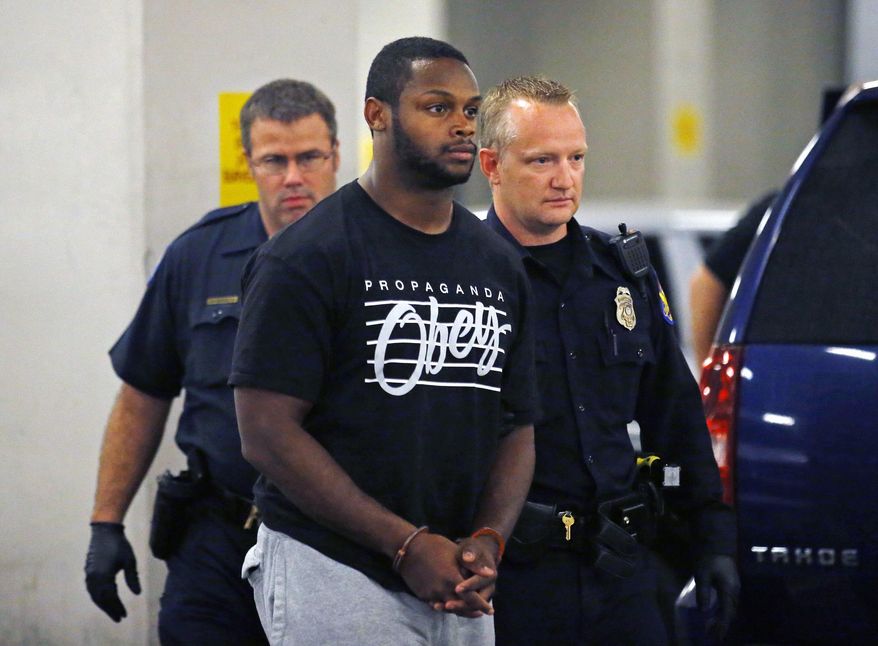 Phoenix police officers escort Arizona Cardinals running back Jonathan Dwyer, to the 4th Avenue Jail following his arrest, Wednesday, Sept. 17, 2014 in Phoenix. Arizona Cardinals running back Jonathan Dwyer was arrested Wednesday on aggravated assault charges in connection with two altercations at his home in July involving a woman and an 18-month-old child, the latest in a string of such cases involving NFL players.(AP Photo/The Arizona Republic, David Kadlubowski) MARICOPA COUNTY OUT; MAGS OUT; NO SALES
