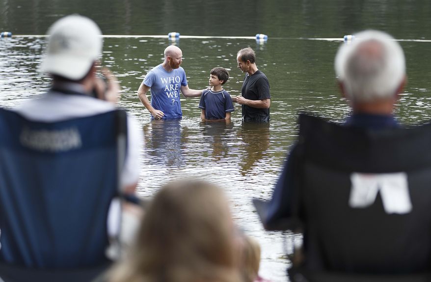 In this Sunday, Aug. 24, 2014 photo, in background, pastors Marshall Benbow, left, and Bill Goans, right, baptize Benjamin Huitt at Lynwood Lakes, in Greensboro, N.C. Once a year, Grace Community Church performs their baptisms outside. (AP Photo/News & Record, Lynn Hey)