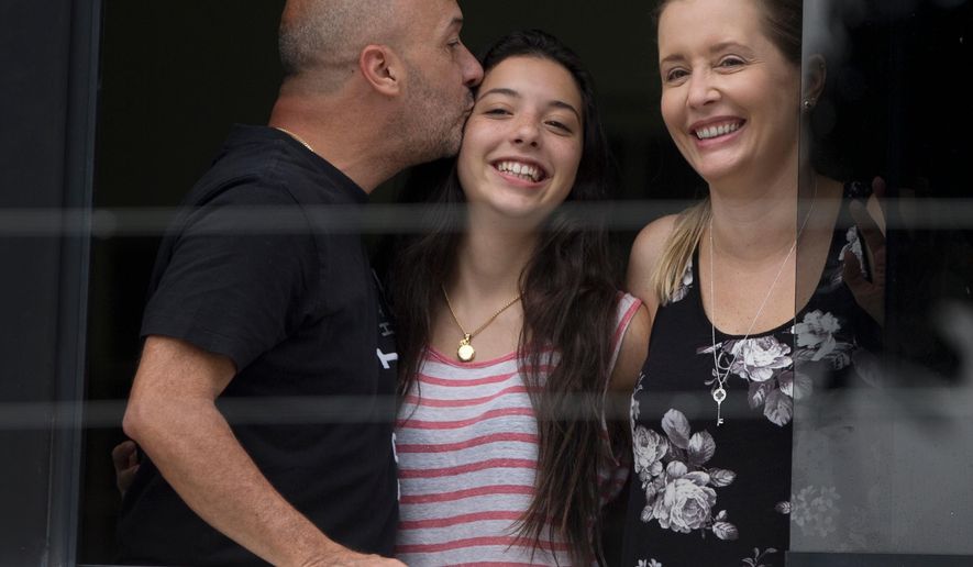 Appearing before journalists, Ivan Simonovis, former Caracas police chief, left, kisses his daughter Ivana, center, as his wife Bony smiles, while standing on the balcony of their home in Caracas, Venezuela, Saturday, Sept. 20, 2014. Simonovis whose decade-long imprisonment had rallied Venezuela’s opposition has been released from jail on humanitarian grounds to continue serving a 30-year sentence at home. Simonovis had been jailed since 2004 in connection with the death of pro-government protesters who had rushed to the defense of then-President Hugo Chavez during a failed coup attempt two years earlier. In 2009, he was convicted of aggravated murder. (AP Photo/Fernando Llano)