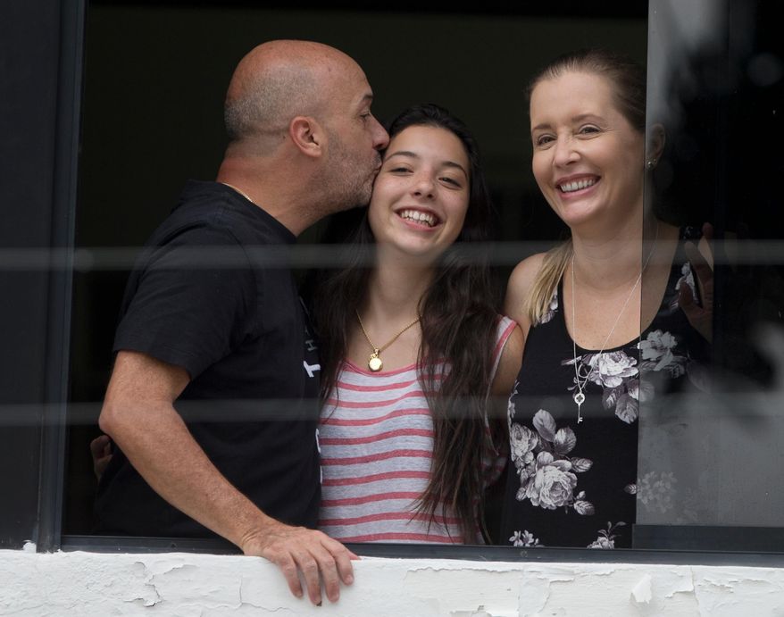Appearing before journalists, Ivan Simonovis, former Caracas police chief, left, kisses his daughter Ivana, center, as his wife Bony smiles, while standing on the balcony of their home in Caracas, Venezuela, Saturday, Sept. 20, 2014. Simonovis whose decade-long imprisonment had rallied Venezuela’s opposition has been released from jail on humanitarian grounds to continue serving a 30-year sentence at home. Simonovis had been jailed since 2004 in connection with the death of pro-government protesters who had rushed to the defense of then-President Hugo Chavez during a failed coup attempt two years earlier. In 2009, he was convicted of aggravated murder. (AP Photo/Fernando Llano)