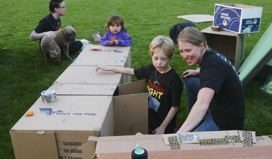 In this photo taken Sept. 13, 2014, Tracyann George shows her son Owen George, 8, one of the cardboard structures they made to sleep in during One Homeless Night in Veteran's Memorial Park in Fairbanks, Alaska. George was one of several dozen who volunteered to spend the night in Veterans Memorial park Saturday to raise awareness of youth homelessness and to raise money for Fairbanks Youth Advocates. The organization operates The Door, a 24-hour shelter at 138 10th Ave. open to any homeless youth younger than 18. (AP Photo/Fairbanks Daily News-Miner, Erin Corneliussen)