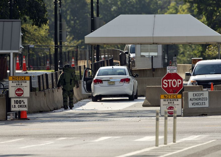 An explosive technician in a bomb suit approaches a vehicle near the entrance to White House in Washington, Saturday. The Secret Service says two men were arrested in separate recent incidents for trying to unlawfully enter the White House. (AP Photo/Pablo Martinez Monsivais)