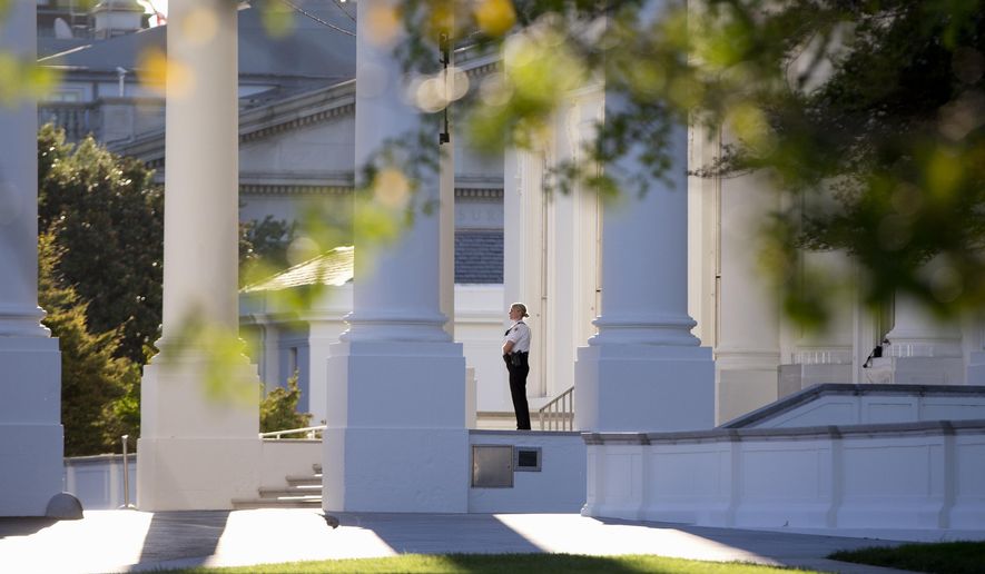 A member of the Secret Service Uniformed Division looks out from the North Portico of the White House in Washington, Monday, Sept. 22, 2014. The Secret Service tightened their guard outside the White House after Friday's embarrassing breach in the security of one of the most closely protected buildings in the world. A man is accused of scaling the White House perimeter fence, running across the lawn and entering the presidential mansion before agents stopped him. (AP Photo/Carolyn Kaster)