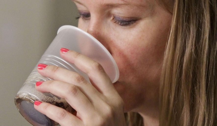 FILE - In this June 27, 2012 file photo, blog writer Stephanie Klose, sips beverage as she participates in a soda taste test in New York. Coke, Pepsi and Dr Pepper on Tuesday, Sept. 23, 2014 said they'll work to reduce the calories Americans get from beverages by 20 percent over the next decade by more aggressively marketing smaller sizes, bottled water and diet drinks. (AP Photo/Bebeto Matthews, File)