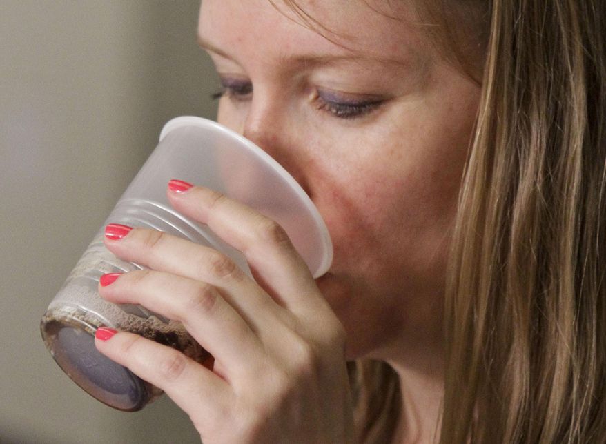 FILE - In this June 27, 2012 file photo, blog writer Stephanie Klose, sips beverage as she participates in a soda taste test in New York. Coke, Pepsi and Dr Pepper on Tuesday, Sept. 23, 2014 said they'll work to reduce the calories Americans get from beverages by 20 percent over the next decade by more aggressively marketing smaller sizes, bottled water and diet drinks. (AP Photo/Bebeto Matthews, File)