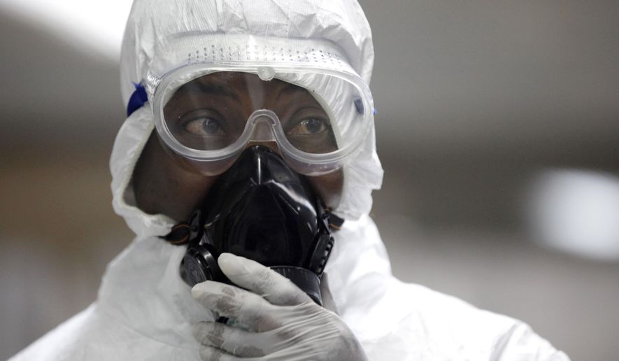 FILE - In this Aug. 4, 2014, file photo, a Nigerian health official wearing a protective suit waits to screen passengers for the Ebola virus at the arrivals hall of Murtala Muhammed International Airport in Lagos, Nigeria. Six months into the biggest-ever Ebola outbreak, scientists say they’ve learned more about how the potentially lethal virus behaves and how future outbreaks might be stopped. The first cases of Ebola were reported in Guinea by the World Health Organization on March 23 before spreading to Sierra Leone, Liberia and elsewhere. (AP Photo/Sunday Alamba, File)