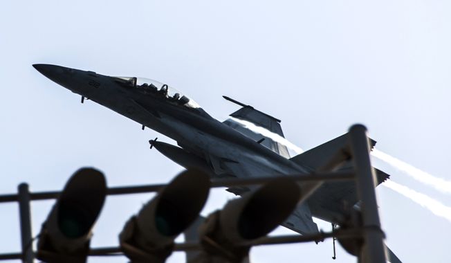 In this image provided by the U.S. Navy a F/A-18F Super Hornet attached to the Fighting Black Lions of Strike Fighter Squadron flies over the aircraft carrier USS George H.W. Bush in the Persian Gulf on Tuesday, Sept. 23, 2014, after conducting strike missions against Islamic State group targets in Syria. (AP Photo/U.S. Navy, Mass Communication Specialist 3rd Class Brian Stephens)