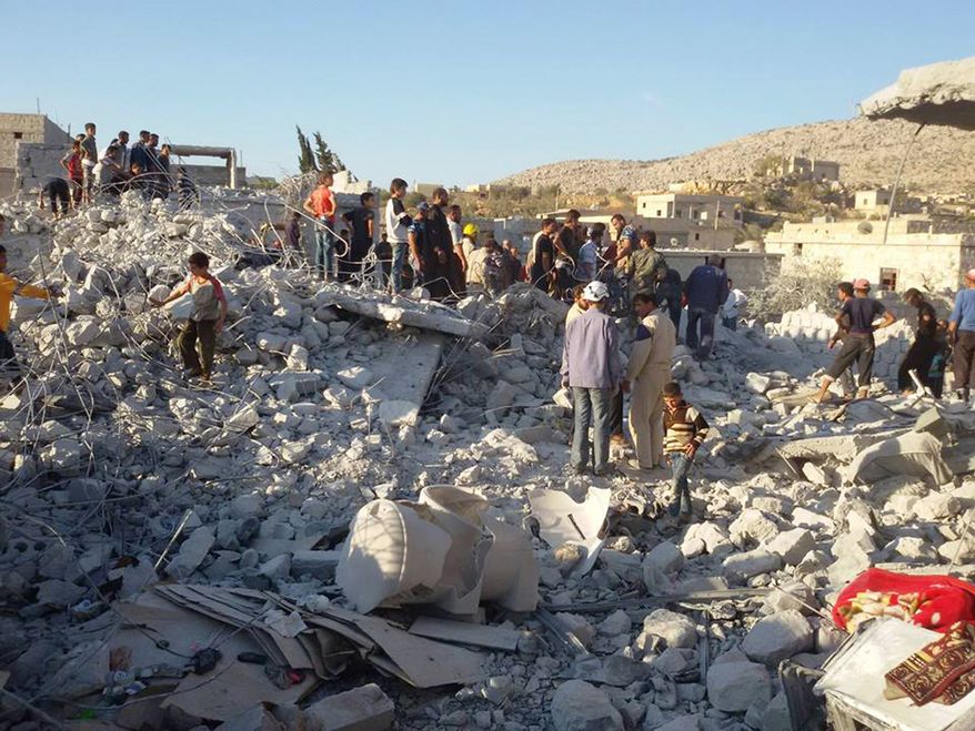 This photo provided by an anti-Bashar Assad activist group Edlib News Network (ENN), which has been authenticated based on its contents and other AP reporting, shows Syrian citizens checking a damaged house that they say was targeted by the coalition airstrikes, in the village of Kfar Derian, a base for the al-Qaida-linked Nusra Front, a rival of the Islamic State group, between the northern province of Aleppo and Idlib, Syria, Tuesday Sept. 23, 2014. Syria said Tuesday that Washington informed President Bashar Assad's government of imminent U.S. airstrikes against the Islamic State group, hours before an American-led military coalition pounded the extremists' strongholds across northern and eastern Syria. (AP Photo/Edlib News Network ENN)