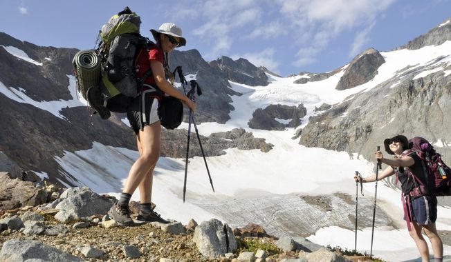 FILE - In this August 2013 file photo, Holly Weiler, left, and Samantha Journot of the Spokane Mountaineers hike past Lyman Glacier as they head toward Spider Gap to complete a loop backpacking trek in Washington state&#x27;s Glacier Peak Wilderness. The U.S. Forest Service is proposing rules that restrict filming and photography by media organizations and others in more than 100 million acres of the nation&#x27;s wilderness, Wednesday, Sept. 24, 2014.  (AP Photo/The Spokesman-Review, Rich Landers, File) COEUR D&#x27;ALENE PRESS OUT