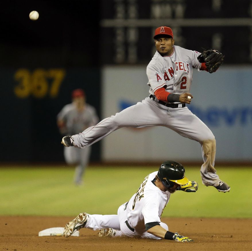 Los Angeles Angels shortstop Erick Aybar hops over Oakland Athletics' Josh Reddick after completing a double play in the seventh inning of a baseball game Tuesday, Sept. 23, 2014, in Oakland, Calif. Oakland's Geovany Soto was out at first base. (AP Photo/Ben Margot)