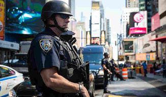 A New York City cop stands watch in Times Square. (Associated Press) ** FILE **