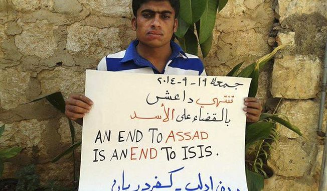 This Friday, Sept. 19, 2014 photo, provided by Edlib News Network (ENN),  an anti-Bashar Assad activist group, which has been authenticated based on its contents and other AP reporting, shows an anti-Syrian government protester holding a placard during a demonstration against the U.S.-led coalition airtstrikes, at the village of Kfar Derian, Idlib province, northern Syria.  The U.S. is struggling to counter anger among the Syrian opposition, where many believe that the air campaign against extremists in the country is only helping President Bashar Assad and that Washington is coordinating with Damascus, despite American insistence it backs the rebel cause. (AP Photo/Edlib News Network ENN)