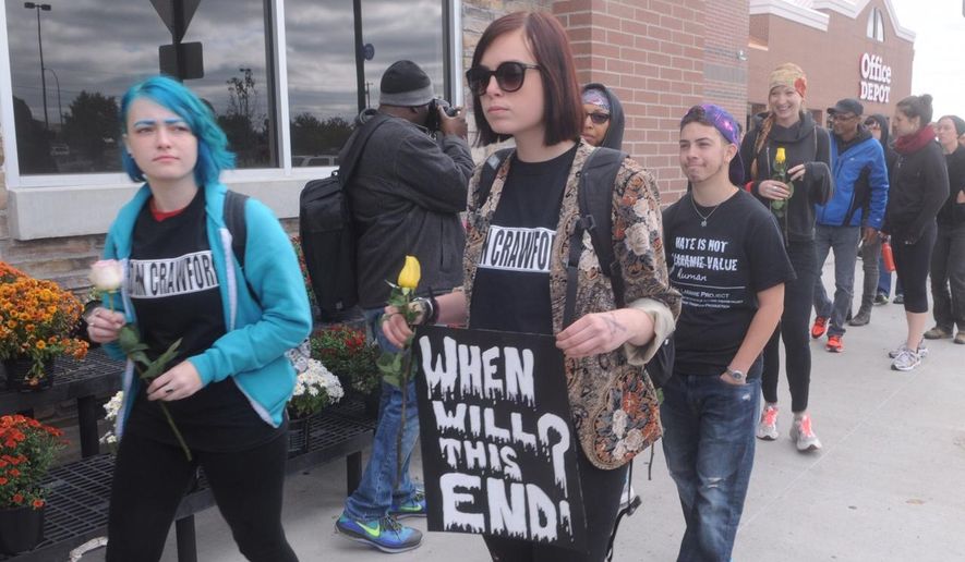 FILE - In this Sept. 22, 2014 file photo, demonstrators walk in front of the Beavercreek, Ohio, Wal-Mart, where customer John Crawford III was shot and killed by police Aug. 5. The family of Crawford says soundless surveillance video shows their actions were unreasonable. But a prosecutor cited the same video to explain the shooting was justified. (AP Photo/The Dayton Daily News, Marshall Gorby, File) LOCAL PRINT OUT; LOCAL TELEVISION OUT; WKEF-TV OUT; WRGT-TV OUT; WDTN-TV OUT