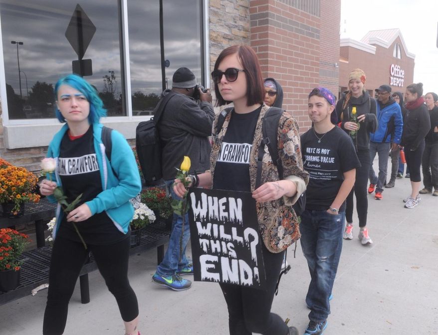 FILE - In this Sept. 22, 2014 file photo, demonstrators walk in front of the Beavercreek, Ohio, Wal-Mart, where customer John Crawford III was shot and killed by police Aug. 5. The family of Crawford says soundless surveillance video shows their actions were unreasonable. But a prosecutor cited the same video to explain the shooting was justified. (AP Photo/The Dayton Daily News, Marshall Gorby, File) LOCAL PRINT OUT; LOCAL TELEVISION OUT; WKEF-TV OUT; WRGT-TV OUT; WDTN-TV OUT