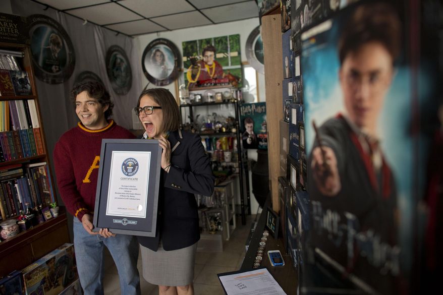 Johanna Hessling of Guinness World Records, right, presents Menahem Asher Silva Vargas, a 37 year old lawyer, with a certificate recognizing him as the title holder for the largest collection of Harry Potter memorabilia, at his home in Mexico City, Monday, Sept. 29, 2014. Silva's 14 year old collection consists of more than 3000 individual items, including figurines, trading cards, wands, clothing, and accessories.(AP Photo/Rebecca Blackwell)